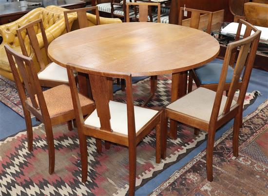 A Gordon Russell oak drop flap dining table and eight Enstone oak chairs Table 146cm diameter extended